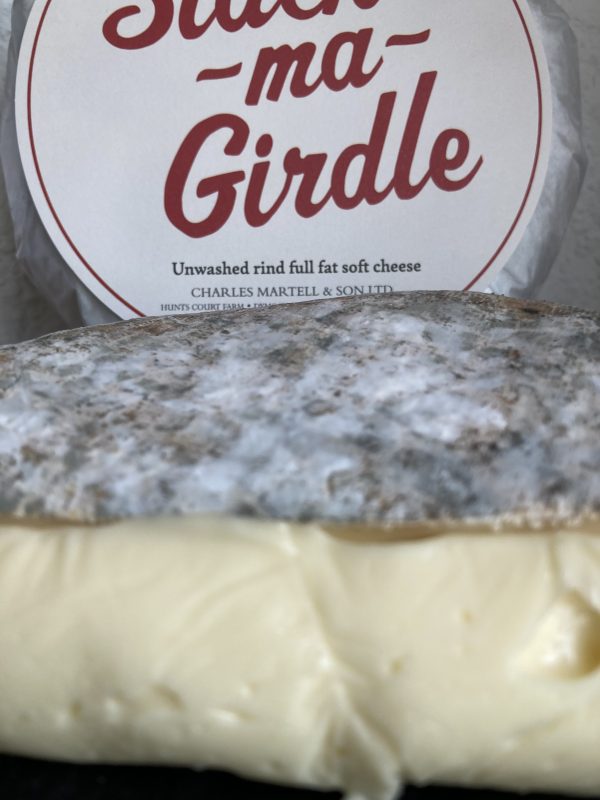 Extreme close up of oozy Slack Ma Girdle creamy cheese with round whole cheese in background