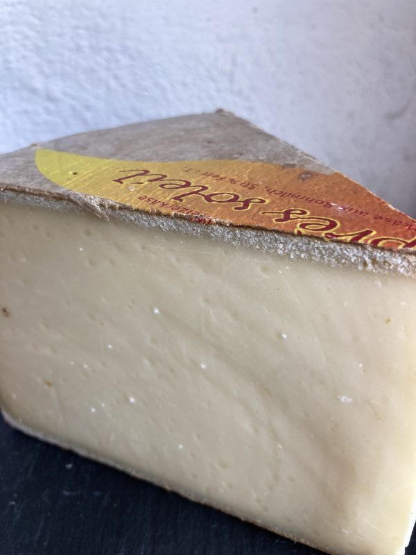 Pale, hard triangular wedge of Apres Soleil Alpine cheese